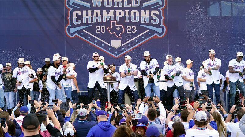 FILE - The Texas Rangers, on stage, spray champagne on fans during a World Series baseball...