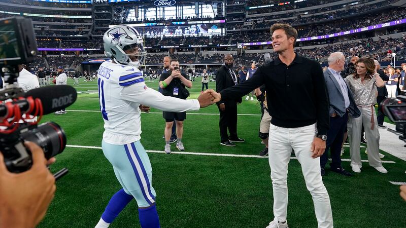 Dallas Cowboys linebacker Micah Parsons, left, greets Tom Brady, right, on the field during...