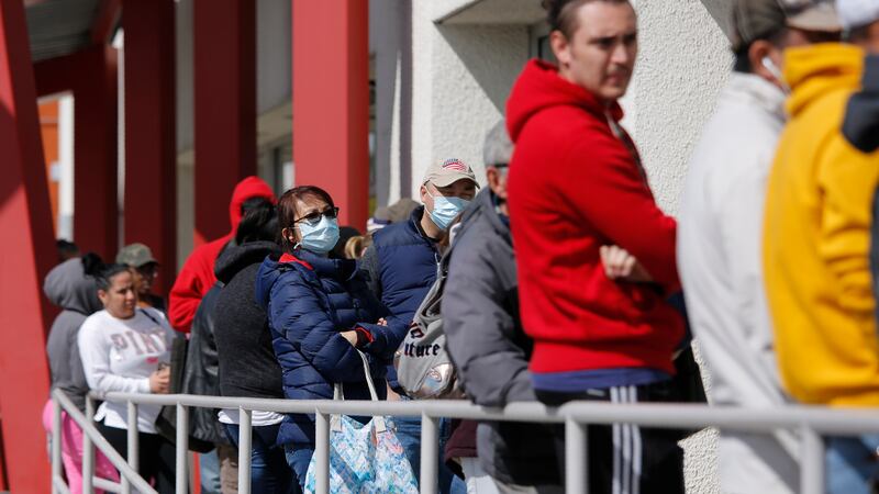 In this March 17, 2020 file photo, people wait in line for help with unemployment benefits at...