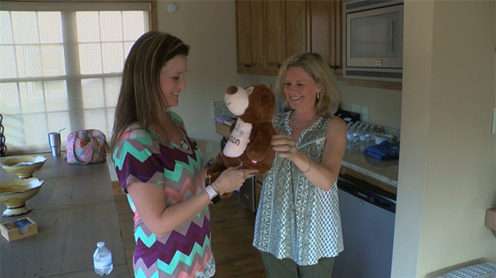 Facilitator Jennifer Carson presents Tiffany Ayers with a bear embroidered with the name of...