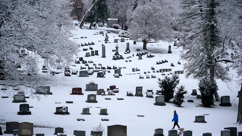 FILE - A man walks through the snow covered Mount Lebanon Cemetery in Mount Lebanon, Pa., on...