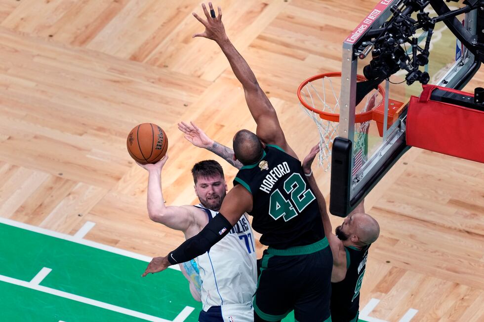 Dallas Mavericks guard Luka Doncic (77) looks to pass the ball while covered by Boston Celtics...